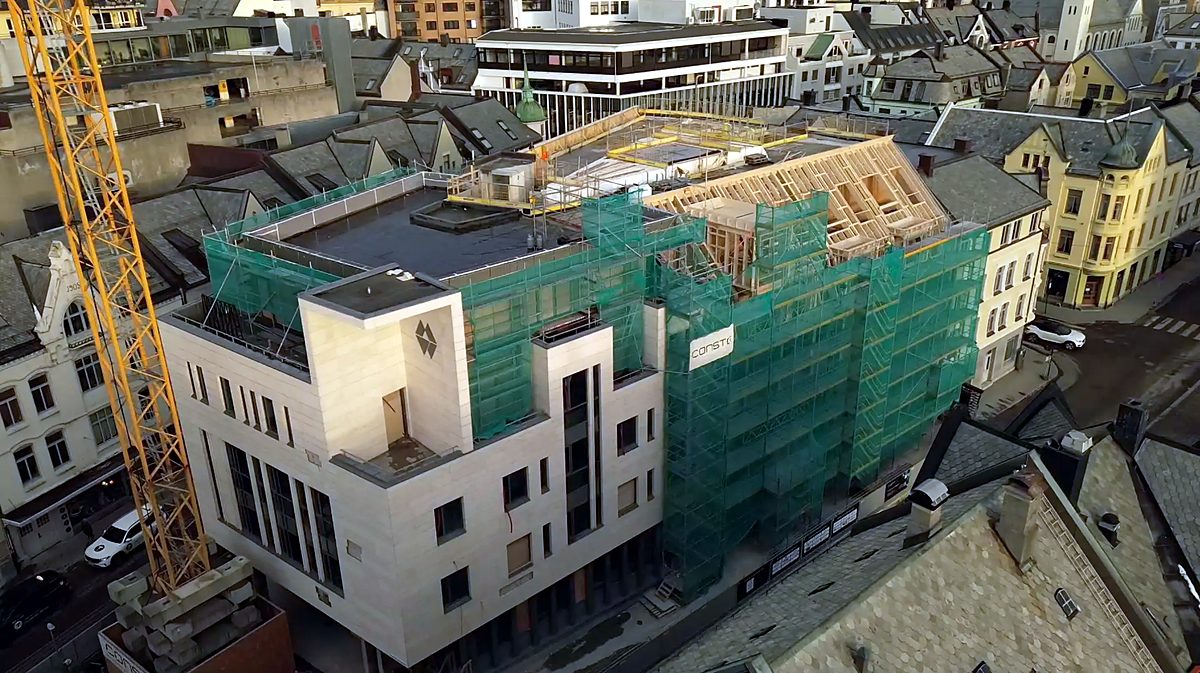 Fugleperspektiv av bygg under arbeid med stillas, sikkerhetsnett og takkonstruksjon